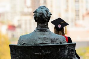 A photo of a back of a statue and a student on UW-Madison campus