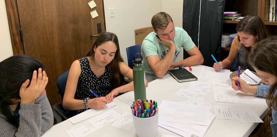 A photo of Spanish-language Writing Center students sitting around a desk